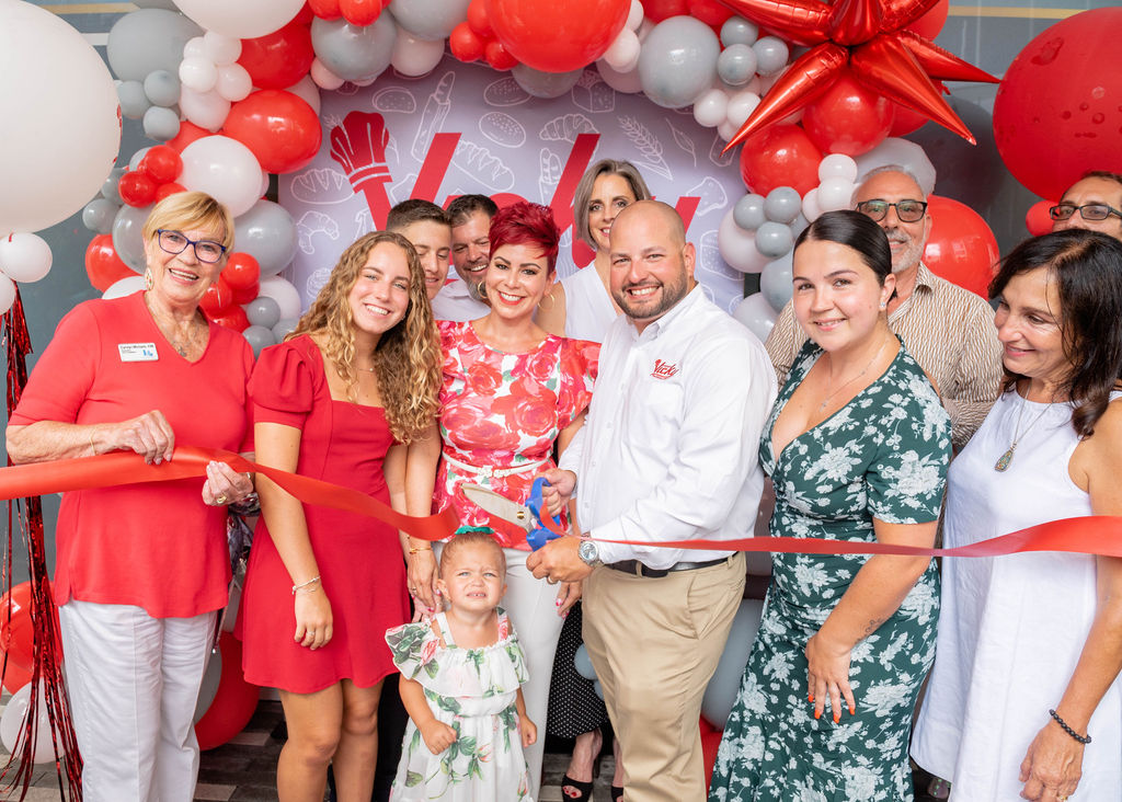Vicky Bakery team celebrating ceremony at Vicky Bakery, standing under a festive red, white, and silver balloon arch with the brand logo in the background.